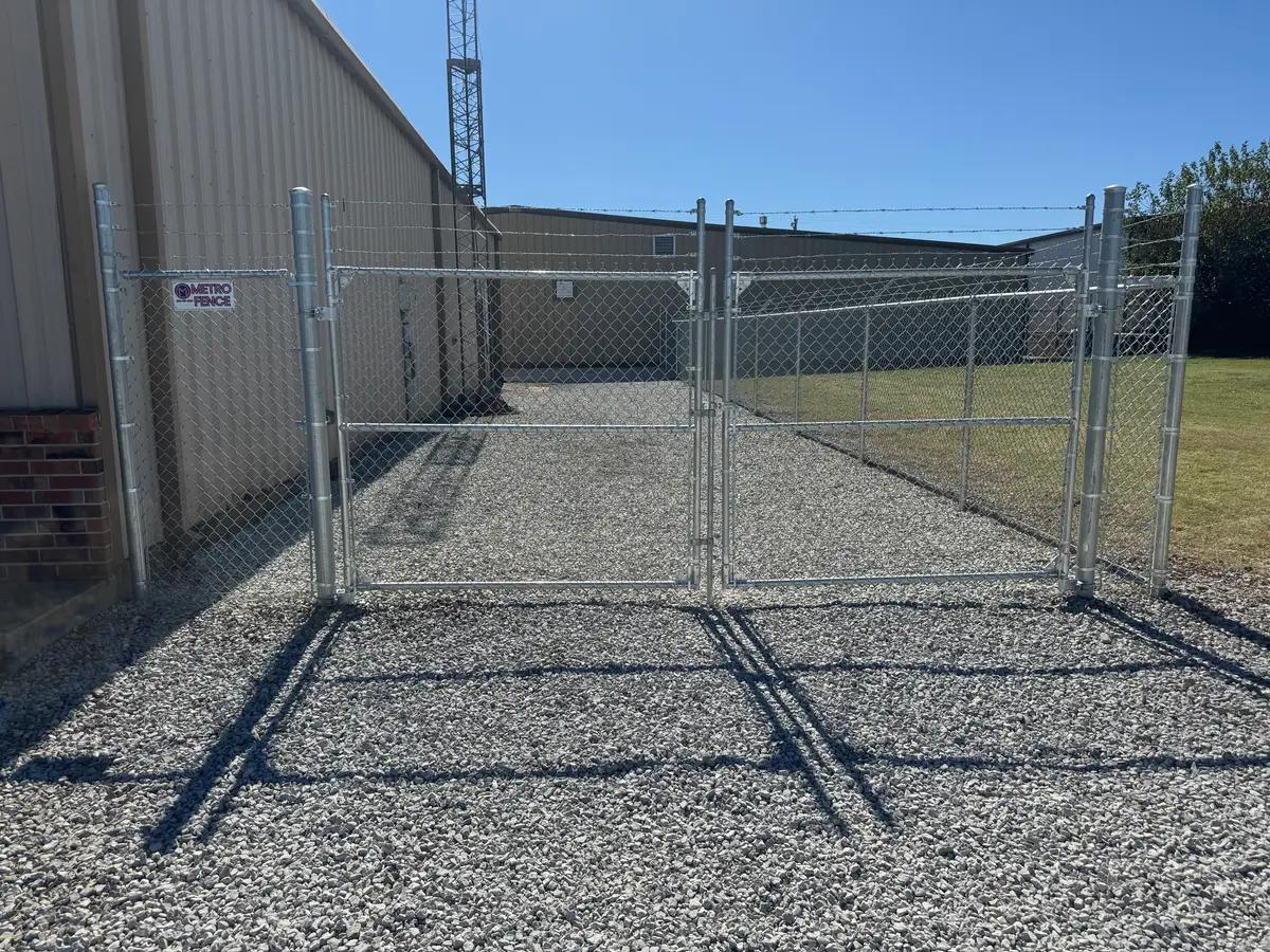 Galvanized commercial chain link fence with a barbed wire top and double drive gates at an Oklahoma City business