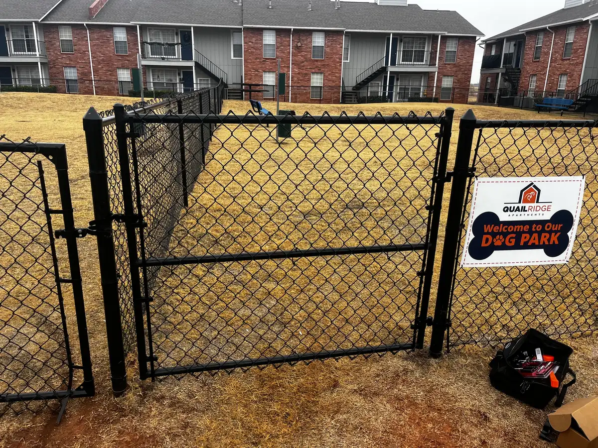 Black chain link fence and gate enclosing a dog park at an Oklahoma City apartment community