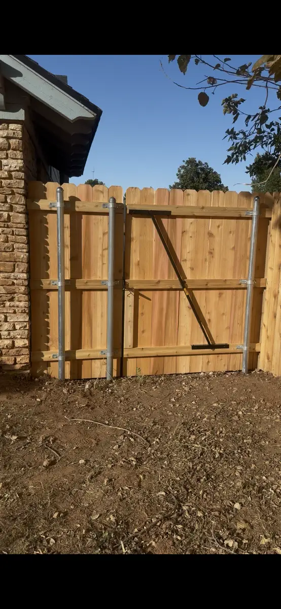 Close-up of a galvanized steel post and brace behind a cedar privacy fence