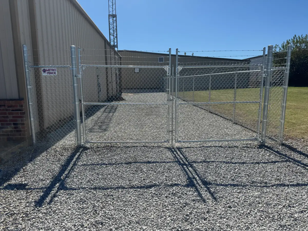 Galvanized commercial chain link fence with a barbed wire top and double drive gates at an Oklahoma City business