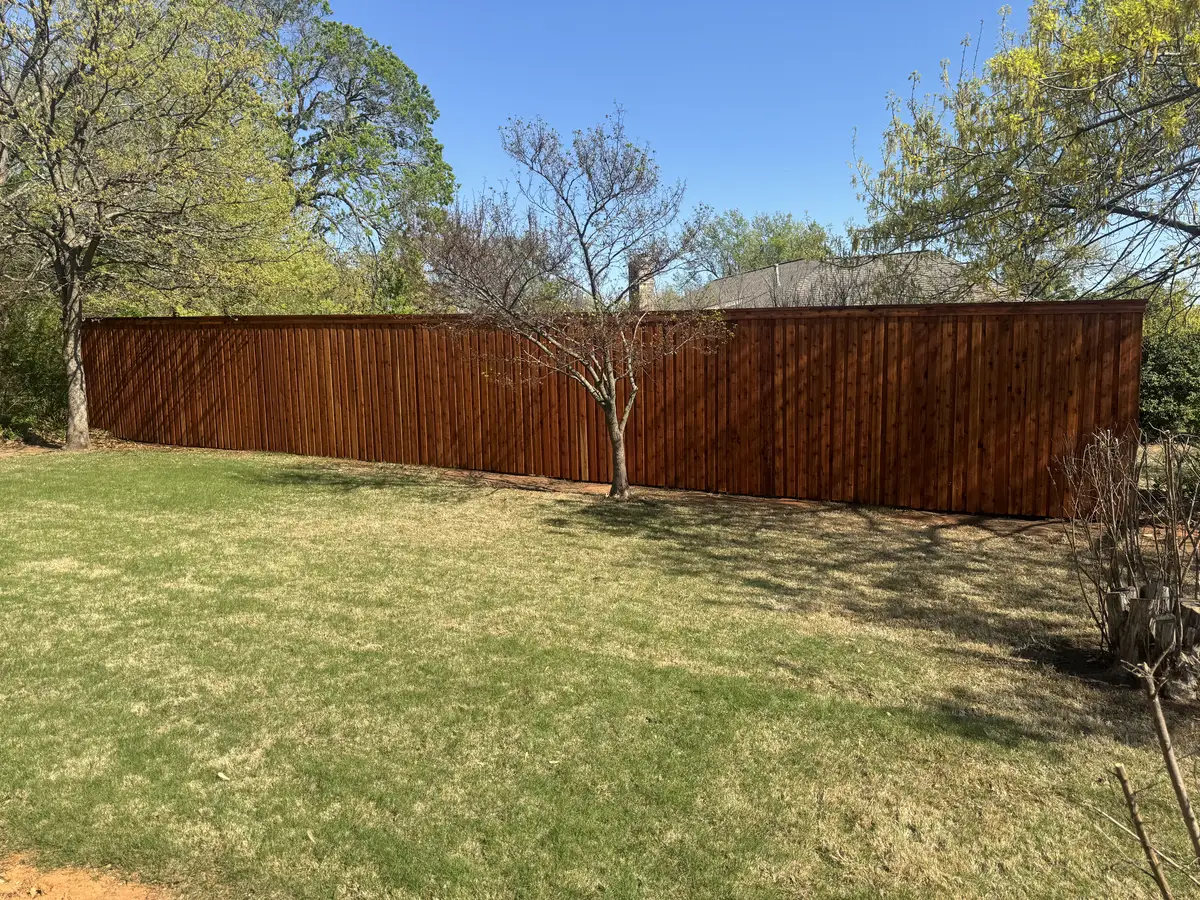 Stained cedar privacy fence around a wooded Oklahoma City back yard